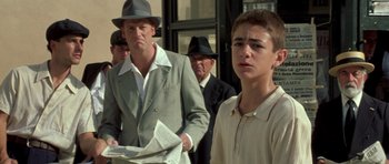 Movie still from “Malena” (2000), directed by Giuseppe Tornatore – A group of men standing next to each other on the street; Medium shot, Low angle