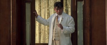 Movie still from “Malena” (2000), directed by Giuseppe Tornatore – A man wearing a white suit and holding a wine glass; Medium shot, Low angle