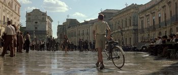 Movie still from “Malena” (2000), directed by Giuseppe Tornatore – A man with a bicycle in the middle of a street; Wide shot, High angle