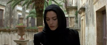 Movie still from “Malena” (2000), directed by Giuseppe Tornatore – A woman in a black hooded jacket looking down at her face; Close Up shot, Low angle