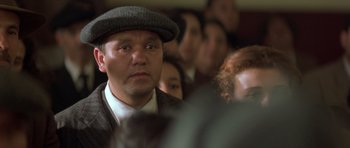 Movie still from “Malena” (2000), directed by Giuseppe Tornatore – A person wearing a hat in front of a crowd; Close Up shot, Low angle
