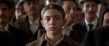 Movie still from “Malena” (2000), directed by Giuseppe Tornatore – A young man in a crowd of people; Close Up shot, Low angle