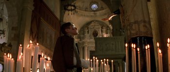 Movie still from “Malena” (2000), directed by Giuseppe Tornatore – A young man in a church with a candle; Medium shot, Low angle