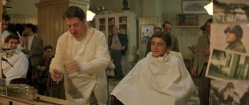 Movie still from “Malena” (2000), directed by Giuseppe Tornatore – A man sitting in front of another man in a barber shop; Medium shot, Over the shoulder angle