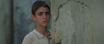 Movie still from “Malena” (2000), directed by Giuseppe Tornatore – A young man standing next to a wall; Close Up shot, Low angle