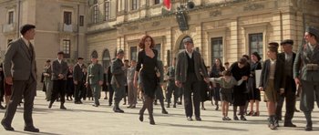 Movie still from “Malena” (2000), directed by Giuseppe Tornatore – A group of people walking down a street; Wide shot, Low angle