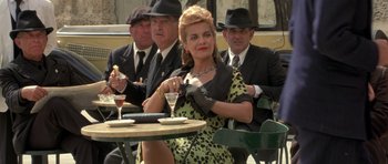 Movie still from “Malena” (2000), directed by Giuseppe Tornatore – A woman sitting at an outdoor table with two men; Medium shot, Over the shoulder angle
