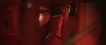 Movie still from “Malena” (2000), directed by Giuseppe Tornatore – A man in a suit and hat standing in the dark; Close Up shot, Low angle