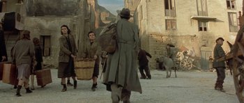 Movie still from “Malena” (2000), directed by Giuseppe Tornatore – A group of people walking down a street; Wide shot, High angle