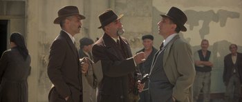 Movie still from “Malena” (2000), directed by Giuseppe Tornatore – A group of men standing next to each other wearing hats; Medium shot, Over the shoulder angle