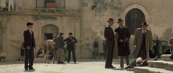 Movie still from “Malena” (2000), directed by Giuseppe Tornatore – A group of men standing on the side of the street; Wide shot, Low angle