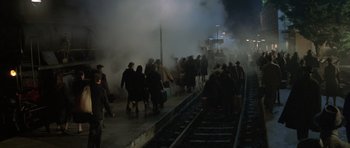 Movie still from “Malena” (2000), directed by Giuseppe Tornatore – A group of people walking along a train track at night; Extreme Wide shot, High angle