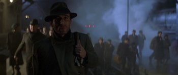 Movie still from “Malena” (2000), directed by Giuseppe Tornatore – A group of people in a dark area with smoke; Medium shot, Low angle