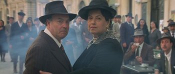 Movie still from “Malena” (2000), directed by Giuseppe Tornatore – A man and a woman wearing hats and posing for a picture; Medium shot, Low angle