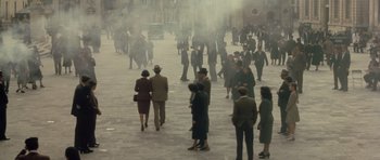 Movie still from “Malena” (2000), directed by Giuseppe Tornatore – A group of people walking down a street; Extreme Wide shot, High angle