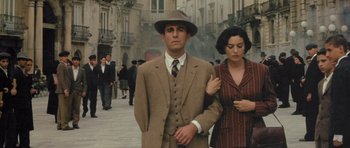 Movie still from “Malena” (2000), directed by Giuseppe Tornatore – A man and a woman walking down a street; Medium shot, High angle