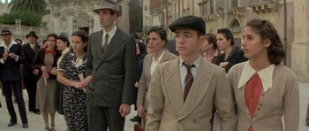 Movie still from “Malena” (2000), directed by Giuseppe Tornatore – A group of men in suits and hats on a street; Medium shot, Low angle