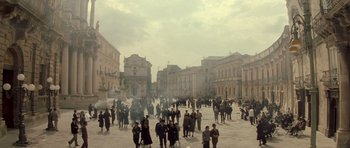 Movie still from “Malena” (2000), directed by Giuseppe Tornatore – A crowd of people standing on a street; Extreme Wide shot, High angle