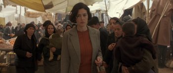 Movie still from “Malena” (2000), directed by Giuseppe Tornatore – A woman in a crowd of people in a building; Medium shot, Over the shoulder angle