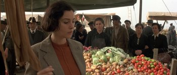 Movie still from “Malena” (2000), directed by Giuseppe Tornatore – A woman standing in front of a pile of vegetables; Medium shot, Over the shoulder angle