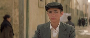 Movie still from “Malena” (2000), directed by Giuseppe Tornatore – A young man in a suit and a hat; Close Up shot, Low angle