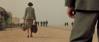 Movie still from “Malena” (2000), directed by Giuseppe Tornatore – A group of people walking down a road; Wide shot, High angle
