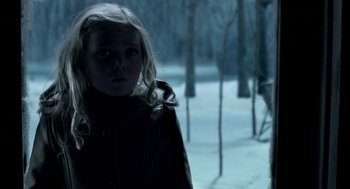 Movie still from “Mama” (2013), directed by Andy Muschietti – A young girl standing in the snow in front of trees; Close Up shot, Over the shoulder angle