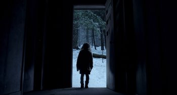Movie still from “Mama” (2013), directed by Andy Muschietti – A person standing in front of an open door in the snow; Wide shot, Low angle