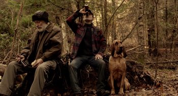 Movie still from “Mama” (2013), directed by Andy Muschietti – Two men and a dog sitting on a bench in the woods; Wide shot, High angle