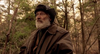 Movie still from “Mama” (2013), directed by Andy Muschietti – An old man with a beard wearing a jacket and a hat; Close Up shot, Low angle