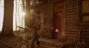 Movie still from “Mama” (2013), directed by Andy Muschietti – A man with a backpack walking down the side of a house; Wide shot, Low angle