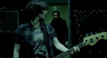 Movie still from “Mama” (2013), directed by Andy Muschietti – A woman holding a guitar in front of a man; Medium shot, Over the shoulder angle