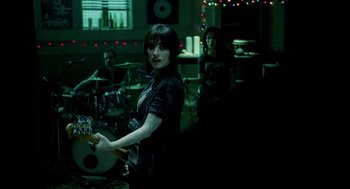 Movie still from “Mama” (2013), directed by Andy Muschietti – A group of people playing instruments in a dark room; Medium shot, Over the shoulder angle