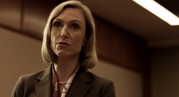 Movie still from “Mama” (2013), directed by Andy Muschietti – A person wearing a suit and a necklace; Close Up shot, Low angle