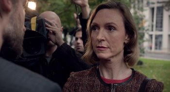 Movie still from “Mama” (2013), directed by Andy Muschietti – A woman is standing in front of a group of people; Close Up shot, Over the shoulder angle