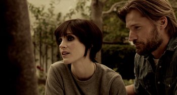 Movie still from “Mama” (2013), directed by Andy Muschietti – A man and a woman sitting next to each other in front of trees; Close Up shot, Over the shoulder angle