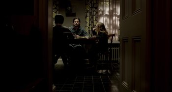 Movie still from “Mama” (2013), directed by Andy Muschietti – A group of people sitting around a table; Wide shot, Over the shoulder angle