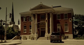 Movie still from “Mama” (2013), directed by Andy Muschietti – A car is parked in front of a large building; Extreme Wide shot, Low angle