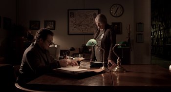 Movie still from “Mama” (2013), directed by Andy Muschietti – A man and a woman working at a desk; Wide shot, High angle
