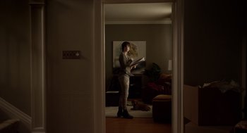 Movie still from “Mama” (2013), directed by Andy Muschietti – A woman standing in a living room holding papers; Wide shot, Low angle