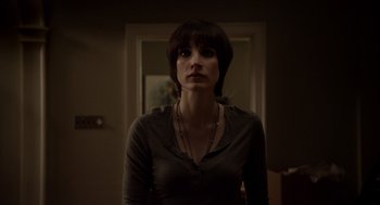 Movie still from “Mama” (2013), directed by Andy Muschietti – A woman standing in front of a door looking at the camera; Close Up shot, Low angle