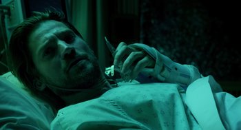 Movie still from “Mama” (2013), directed by Andy Muschietti – A man laying in a hospital bed holding a pair of scissors; Close Up shot, High angle