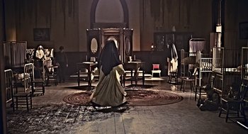 Movie still from “Mama” (2013), directed by Andy Muschietti – A woman dressed as a nun in front of a mirror; Wide shot, High angle