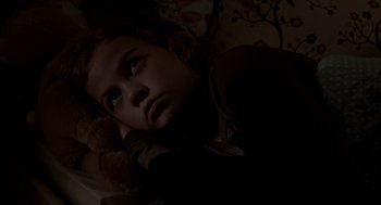 Movie still from “Mama” (2013), directed by Andy Muschietti – A young child laying in bed with a teddy bear; Close Up shot, High angle
