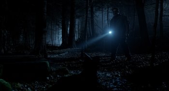 Movie still from “Mama” (2013), directed by Andy Muschietti – A man with a flashlight in the woods at night; Wide shot, Low angle
