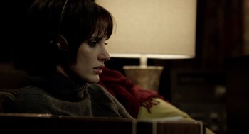 Movie still from “Mama” (2013), directed by Andy Muschietti – A woman wearing headphones sitting on a couch; Close Up shot, Over the shoulder angle