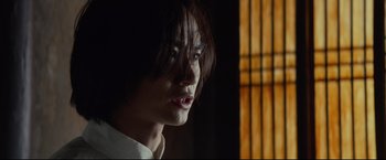 Movie still from “Man of Tai Chi” (2013), directed by Keanu Reeves – A man with long black hair is looking at the camera; Close Up shot, Low angle