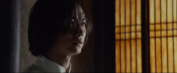 Movie still from “Man of Tai Chi” (2013), directed by Keanu Reeves – A man with long brown hair is looking into the distance; Close Up shot, Low angle