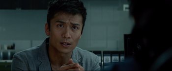 Movie still from “Man of Tai Chi” (2013), directed by Keanu Reeves – A person sitting in front of a window; Close Up shot, Over the shoulder angle