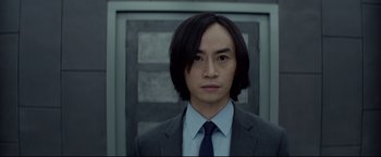 Movie still from “Man of Tai Chi” (2013), directed by Keanu Reeves – A man in a suit and tie standing in front of a door; Close Up shot, Low angle